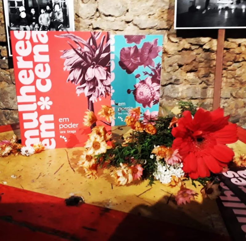 Livro em poder, de Lara Braga, junto a flores.